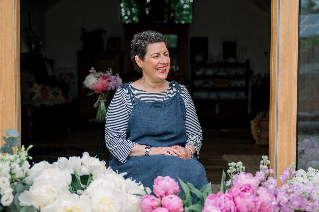 Female Florist business owner sitting in front of a display of flowers