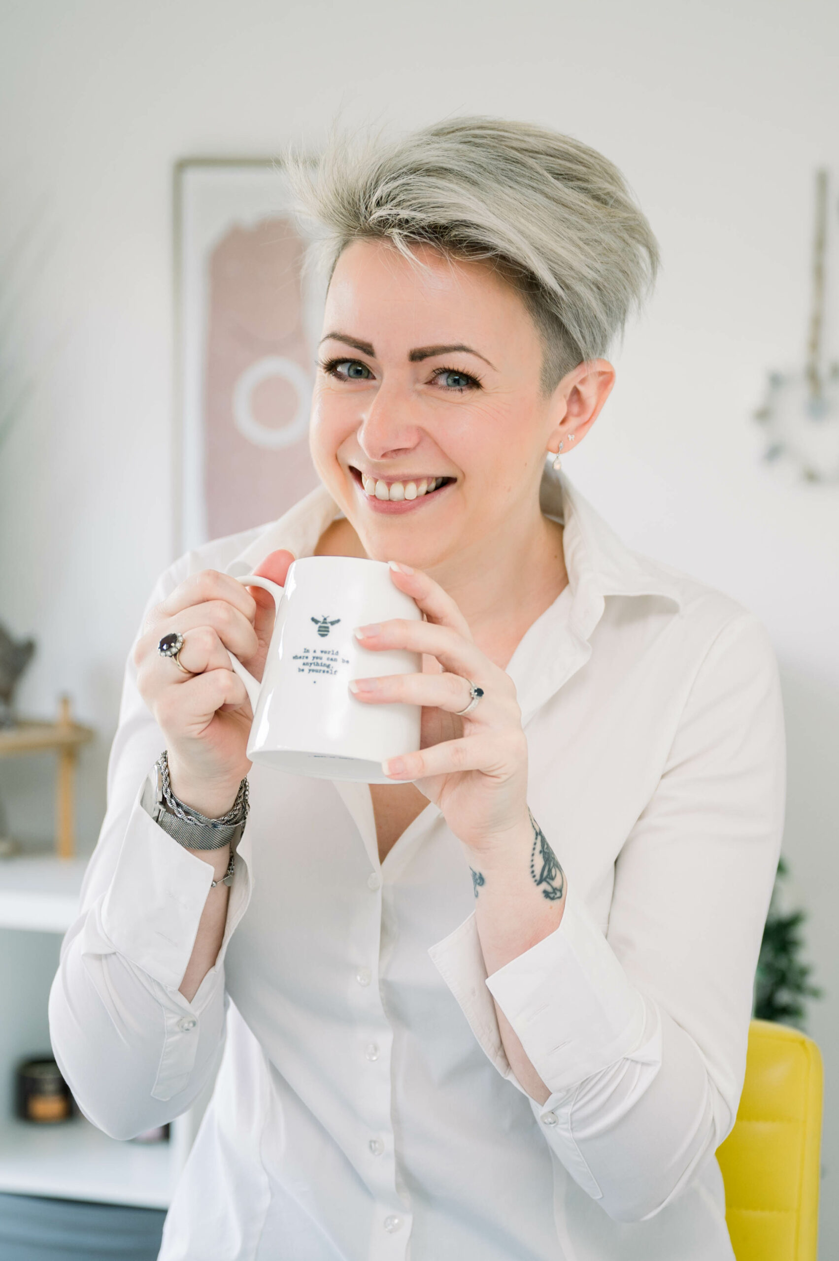 Blonde haired lady smiling to camera with a mug in her hand