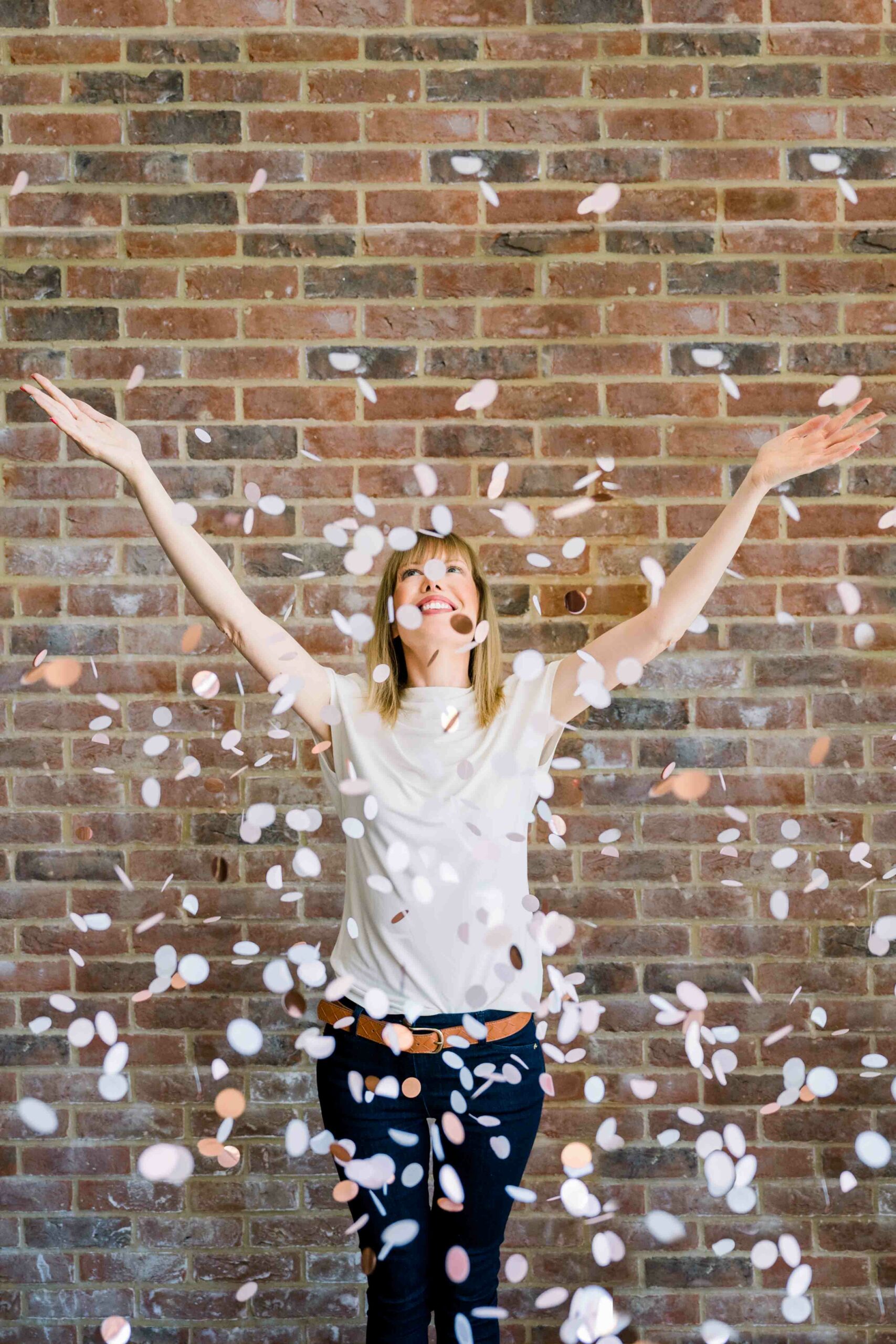 Women throwing confetti in the air in front of a brick wall